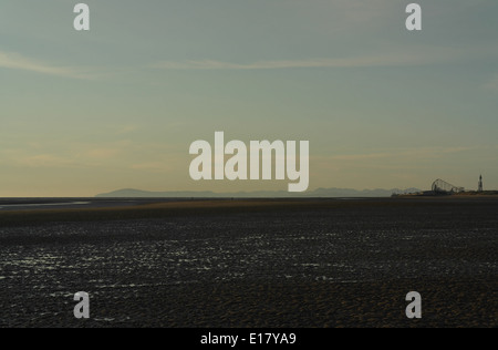 Blauer Himmel Wolkenfetzen Blick auf den Sonnenuntergang, Wellen über St Annes Beach Sand, gegen Blackpool und Cumbrian Mountains, Fylde Küste Stockfoto