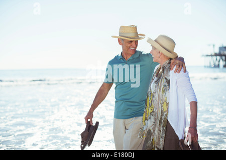 Älteres Paar zu Fuß am Strand Stockfoto