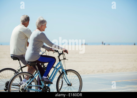 Älteres Paar Fahrrad am Strand Stockfoto