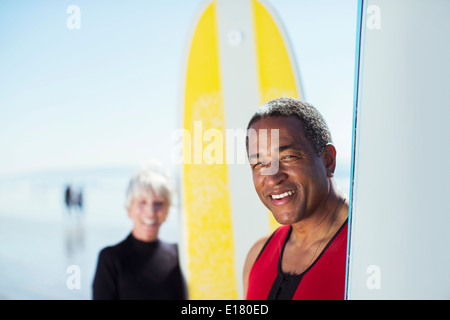 Porträt von älteres Paar mit Surfbrettern am Strand Stockfoto