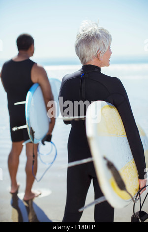 Älteres Paar mit Surfbrettern am Strand Stockfoto