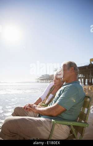 Älteres Paar in Liegestühlen am Strand entspannen Stockfoto