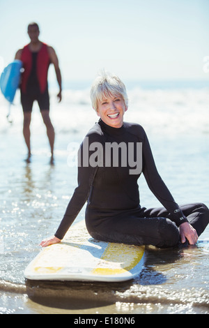 Portrait of senior Woman am Surfbrett am Strand Stockfoto