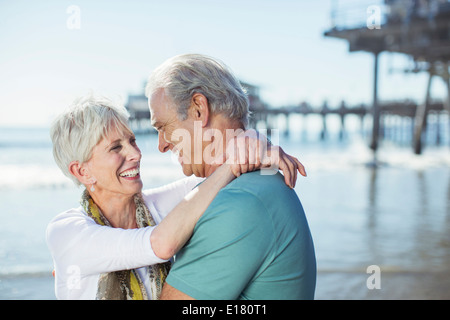 Älteres paar umarmt am Strand Stockfoto