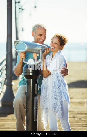 Paar mit Münz-Fernglas auf pier Stockfoto