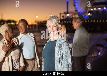 Porträt von enthusiastischen senior Frau mit Freunden am Strand in der Nacht Stockfoto