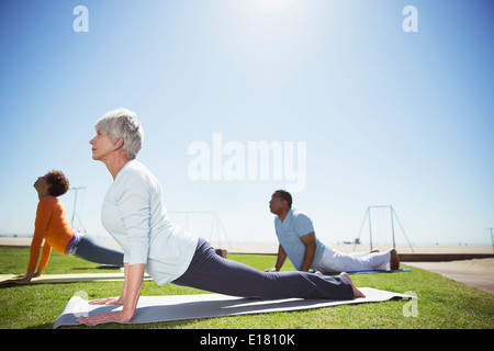 Senioren praktizieren Yoga im sonnigen Beach park Stockfoto