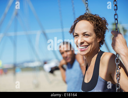 Glückliches Paar auf Schaukel auf Spielplatz Stockfoto