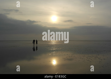 Blick am Abend Sonne reflektiert in nass Strandsand mit zwei Personen zu Fuß in Richtung grau Himmelshorizont, Strand, St. Annes Fylde Küste, UK Stockfoto