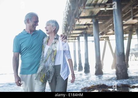 Älteres Paar in der Nähe von Pier am Strand lachen Stockfoto