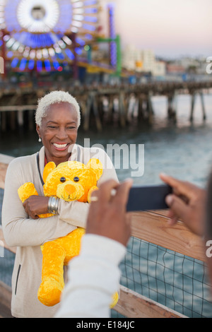 Ältere Frau mit Teddybär posiert für Fotos im Freizeitpark Stockfoto