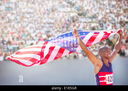 Leichtathletin und Olympiateilnehmerin mit amerikanischen Flagge im Stadion Stockfoto