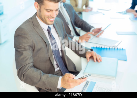 Geschäftsmann SMS mit Handy im Konferenzraum Stockfoto