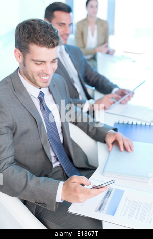 Geschäftsmann SMS mit Handy im Konferenzraum Stockfoto