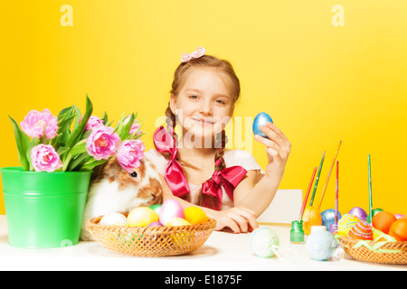 Glückliches Mädchen mit östlichen Eiern und niedlichen Kaninchen Stockfoto