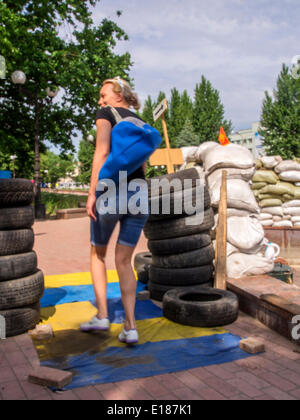 Luhansk, Ukraine. 26. Mai 2014. Junge Frau zu Fuß auf ukrainische Flaggen verteilt auf dem Boden an der Barrikade im Park gegenüber dem Gebäude des ukrainischen Geheimdienstes--die Macht der selbsternannten Volksrepublik Luhansk erwartet Stärkung Durchsetzungsmaßnahmen durch das ukrainische Truppen nach der Auszählung der Stimmen die Präsidentschaftswahlen. Dies wurde durch den Leiter der sogenannten FSC Valery Bolotov Reporter Montag in Lugansk angegeben.  "Wahrscheinlich, nach der endgültigen Auszählung der Stimmen in Kiew aktiven Phase in Kraft," - sagte Bolotow.  Ihm zufolge derzeit halten Sie macht Na Stockfoto