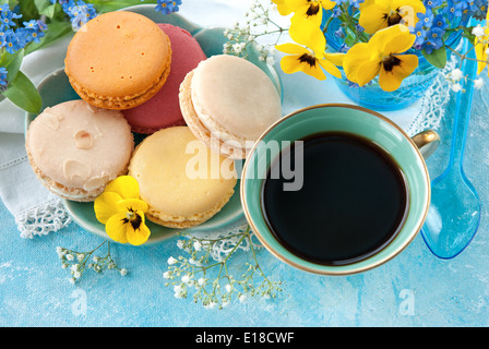 Tasse Kaffee mit Makronen auf einem Tisch mit Frühlingsblumen Stockfoto
