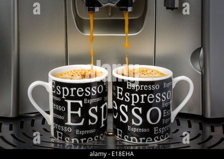 Zwei Espresso-Tassen gefüllt durch eine automatische Espressomaschine Stockfoto
