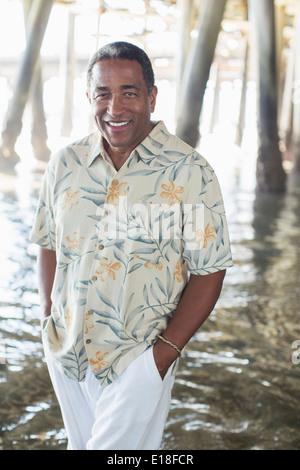 Portrait von zuversichtlich senior Mann unter Pier am Strand Stockfoto