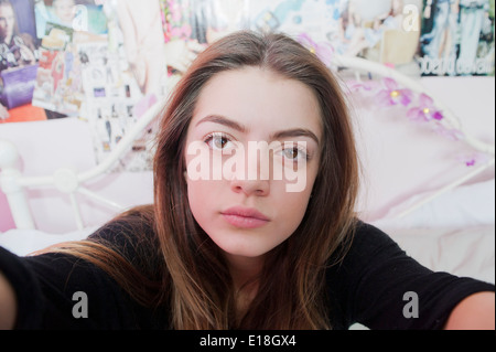 13 Jahre alten Mädchens posieren für ein vorgeben Selfie in ihrem Schlafzimmer Stockfoto