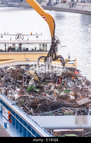 Offenen Schiff geladen oder in einem Kai auf einem städtischen Wasserstraße oder Fluss durch ein heavy-Duty Industriekran abgeladen Stockfoto