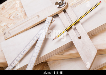 Nahaufnahme eines bunten gelben Tischler Ebene, Herrscher und rechten Winkel liegend auf Planken neue Hartholz zusammen mit einem penci Stockfoto