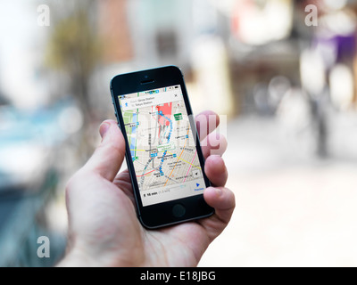 Hand der Person mit dem iPhone anzeigen von Google maps GPS-Navigator auf Straßen von Tokio, Japan. Stockfoto