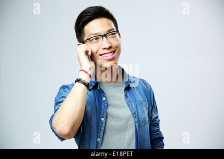 Junger lächelnder Mann reden am Telefon über grauen Hintergrund Stockfoto