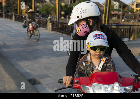 Eine Frau mit ihrem Sohn auf seinem Motorrad überquerte die Brücke über Thu Bon Fluss Stockfoto