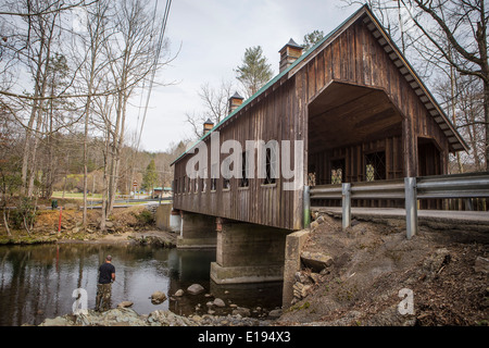 Ein Mann fischt auf Little Pigeon River, durch die Emerts Cove überdachte Brücke in Pittman Center, Tennessee Stockfoto