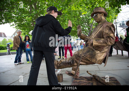 Schwerkraft trotzt gold street Performer, lebende Statue, unterhält die Menschen auf dem Gehweg am Flussufer. Der South Bank, London, UK. Stockfoto