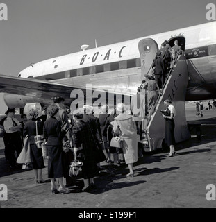 1950er Jahre historische Bild einer Gruppe von gut gekleideten Fluggästen die Schritte auf einem B.O.A.C Flugzeug unter Aufsicht durch eine Luft-stewardess Stockfoto