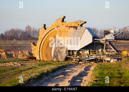Einen riesigen Schaufelradbagger bei der Arbeit in einer Braunkohle pit mine mit einem Feldweg erkennbar, die im Vordergrund Stockfoto
