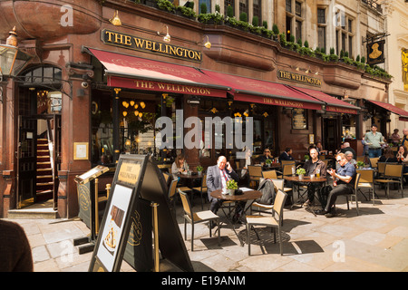 Kunden, die an sonnigen Tischen vor Wellington Pub im Londoner Strand sitzen. Stockfoto