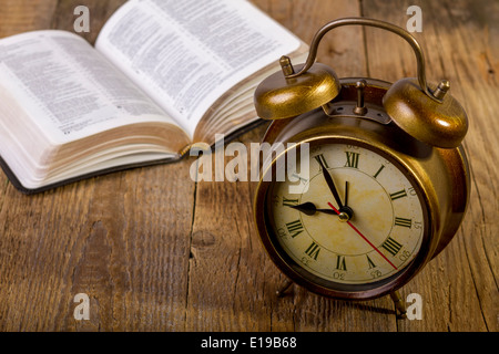 Offene Bibel mit Uhr auf Holz Stockfoto