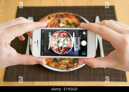 Mit der weißen iPhone Smartphone-Kamera ein Foto von Pizza machen Stockfoto