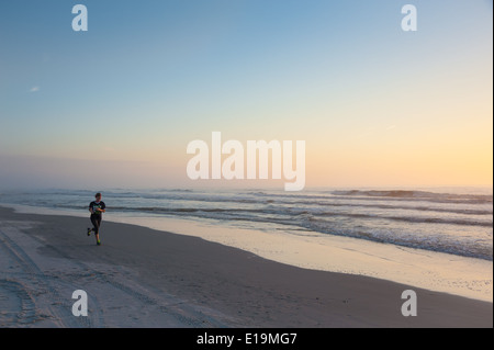 Junge Frau jogging bei Sonnenaufgang am Jacksonville Beach im Nordosten Florida/USA. Stockfoto