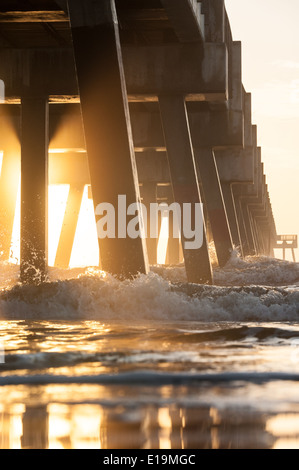 Die aufgehende Sonne beleuchtet einen am frühen Morgennebel unter der Jacksonville Beach Pier im Nordosten Florida/USA. Stockfoto