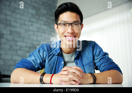 Junge asiatische glücklich am Tisch sitzen Stockfoto