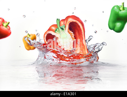 Süße Paprika Multicolors fallen und Spritzwasser in klarem Wasser. Auf weißem Hintergrund. Stockfoto