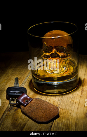 Ein Glas Whiskey mit einem Totenkopf-Eiswürfel mit Autoschlüssel. Stockfoto