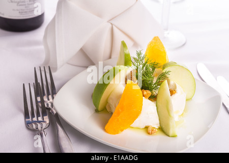 Gespannte Joghurt Labneh Zitrus-Salat mit geschälte Orangen und grünen Äpfeln garniert mit Dill und Walnüssen serviert mit Öl Stockfoto