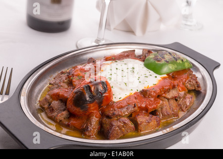 Traditionelle türkische Bursa Iskender Kebap Döner serviert mit speziellen roten Sauce und Joghurt in der Mitte, garniert mit gegrillter Stockfoto