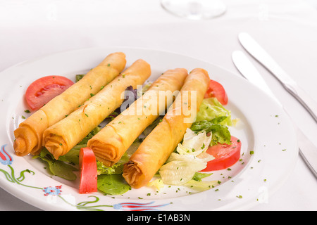 Türkischen Stil gefüllte Filo Teig Käsebrötchen entlang auf Salatblättern zusammen mit Tomaten serviert Stockfoto