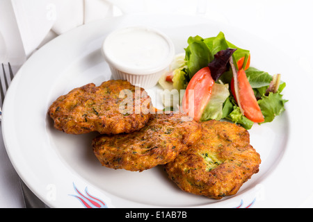 Vegetarische Zucchini Rösti serviert auf einem weißen Teller und garniert mit Gemüse Stockfoto