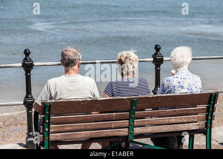 Ältere Menschen, sitzt auf einer Holzbank, genießen den Blick aufs Meer, Llandudno, Strandpromenade, (von hinten) North Wales Großbritannien. Stockfoto