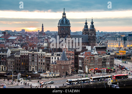 Erhöhte Ansicht von Amsterdam Bahnhofsbereich am Abend mit Verkehr, Sonnenuntergang und Sint Nicolaaskerk Stockfoto