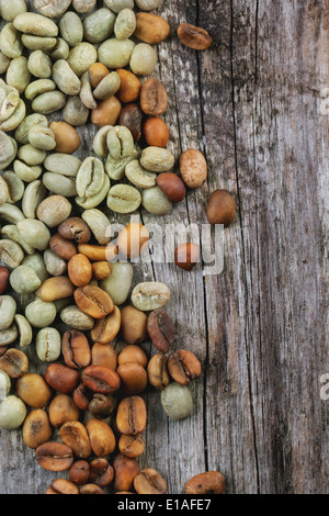 Grüne und braune koffeinfreien ungerösteten Kaffeebohnen über hölzerne Hintergrund. Stockfoto