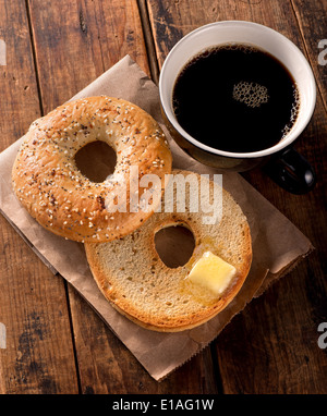 Ein köstliches getoastet alles Bagel mit zerlassener Butter und schwarzen Kaffee. Stockfoto