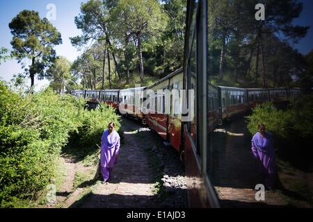 (140529)--HIMACHAL PRADESH, 29. Mai 2013 (Xinhua)--A Dorfbewohner Spaziergänge vorbei an einem Zug in Betrieb an der Kalka-Shimla-Bahn im Nordindiens Himachal Pradesh, 28. Mai 2014. Die Kalka-Shimla Railway ist eine 762? mm-Schmalspur-Eisenbahn im Nordwesten Indiens Himachal Pradesh Reisen eine meist bergige Strecke von Kalka nach Shimla. Es ist bekannt für spektakuläre Aussicht auf die Berge und die umliegenden Dörfer. Die 96-km lange Bahn entstand seit 1898, einen Service für das Hochland von Shimla. Drei immer noch voll funktionsfähige Eisenbahnen, der Darjeeling Himalayan Railway im indischen Westbengalen Stockfoto